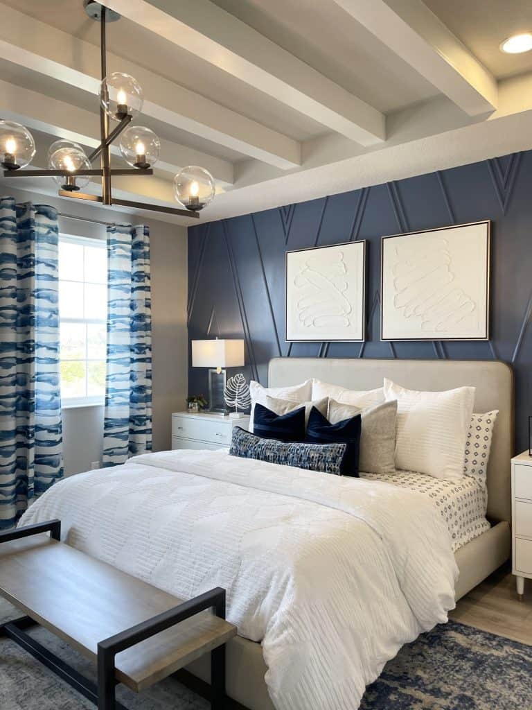 Blue Accent Wall with Molding details behind bed and two pieces of wall art