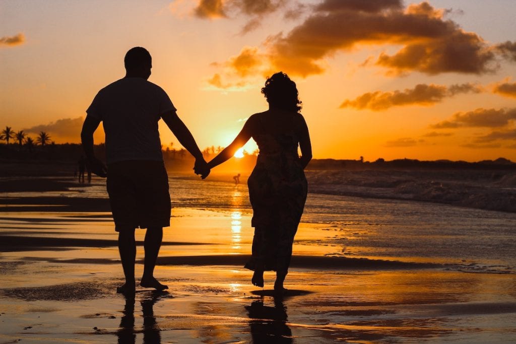 couple holding hands on the beach before sunset
