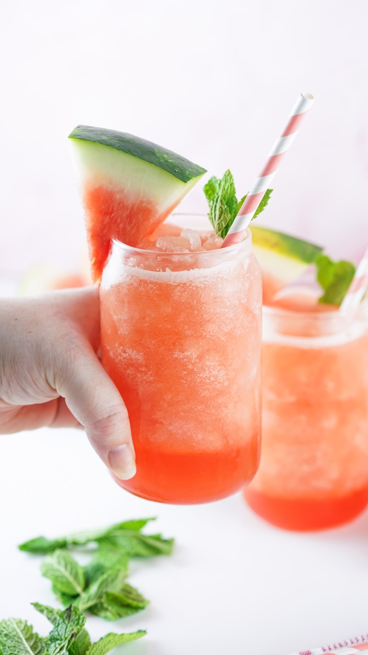 Hand holding a vibrant watermelon slushie.